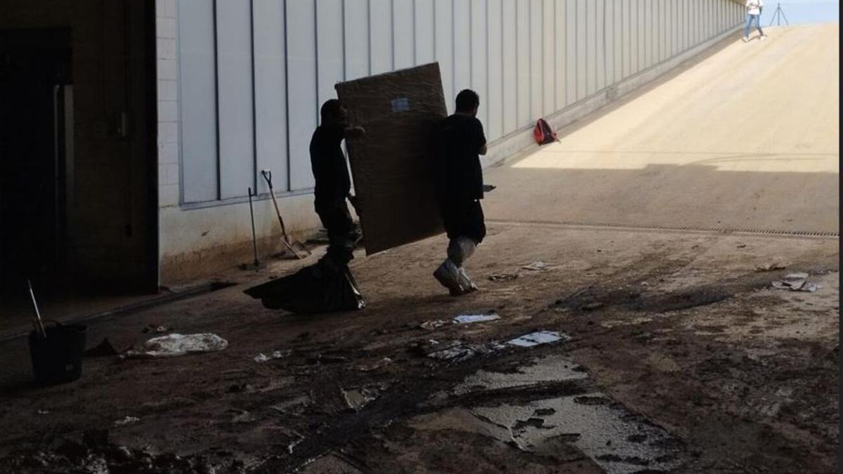 Dos operarios trasladan una de las obras propiedad de la Generalitat dañada por la dana en Riba-roja.