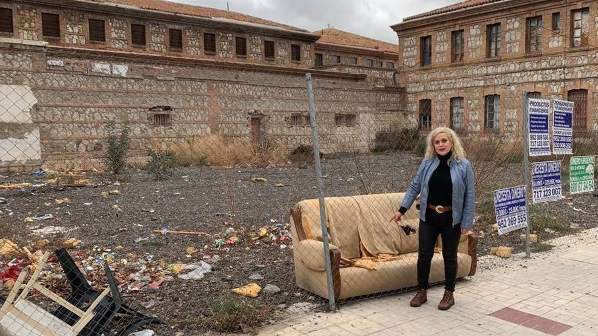 La concejala de Unidas Podemos Remedios Ramos junto a enseres abandonados en la antigua cárcel provincial de Cruz de Humilladero en la capital malagueña