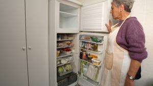 Mujer abre el congelador vacío. 