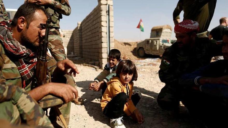 Niños iraquíes junto a varios &quot;peshmerga&quot; kurdos en una posición al este de Mosul. // Reuters