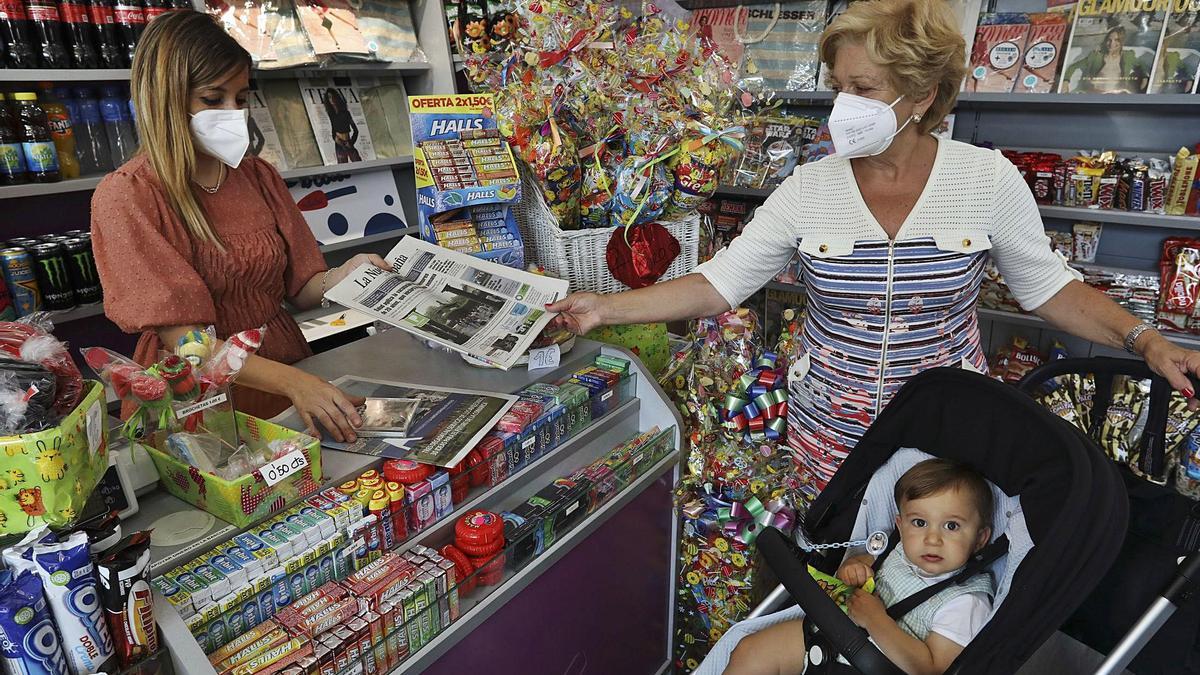 La propietaria del quiosco “Pirulí”, Isabel Fernández, vendiendo el periódico a Mari Feli Alonso. |  LNE