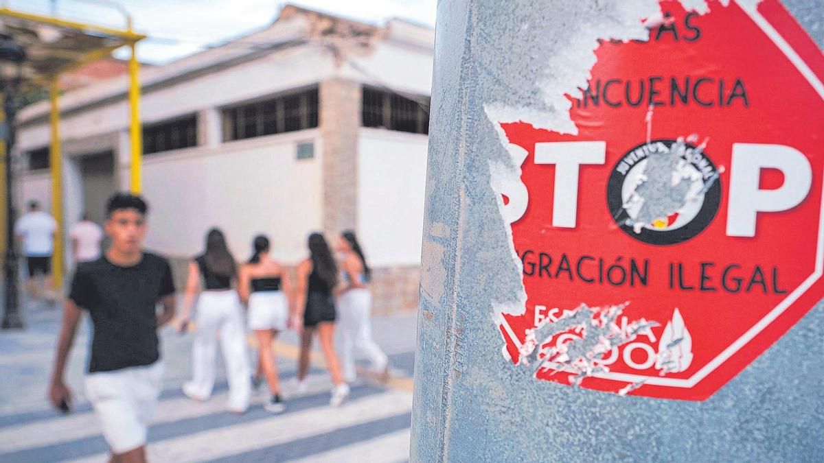 Una pegatina contra la inmigración ilegal medio arrancada en una farola de Torre Pacheco.
