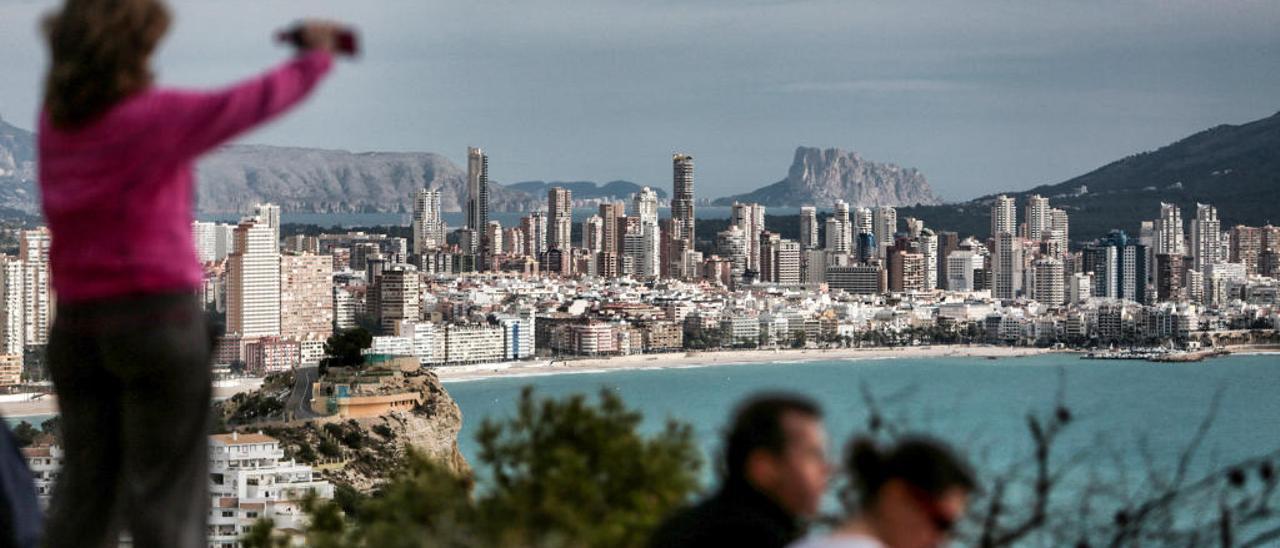 Una mujer capta con su móvil una parte del «skyline» de Benidorm en uno de los sitios más visitados para hacer fotos.