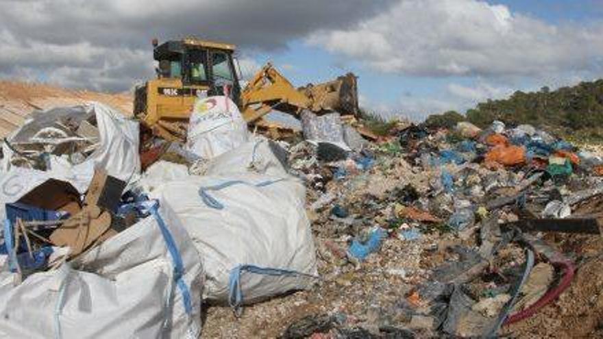 Una retroexcavadora esparce la basura en una celda del vertedero.