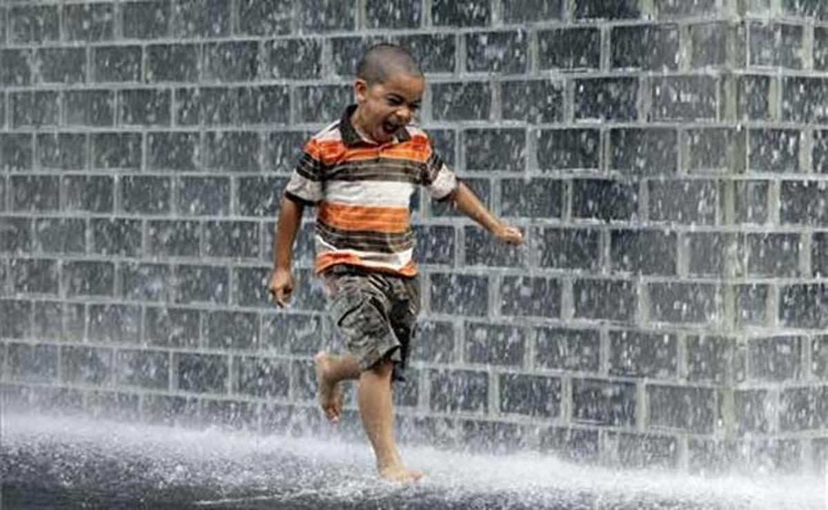 Un nen juga amb l’aigua de la font del Millennium Park, a Chicago.