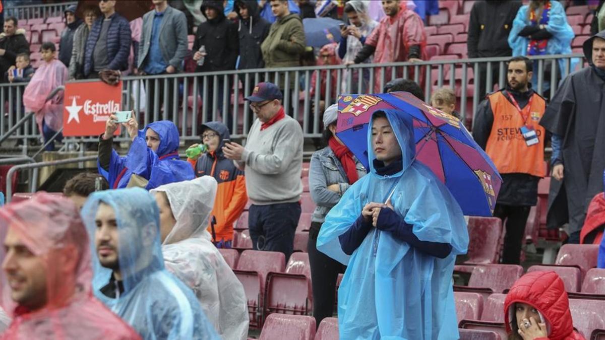 Un seguidor se protege de la lluvia con un paraguas azulgrana