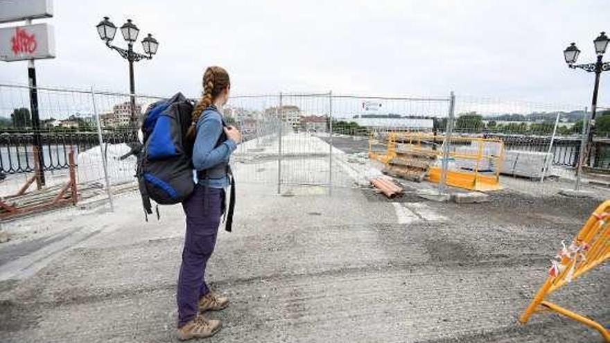 Una peregrina, ante el cerrado puente de O Burgo. // G. Santos