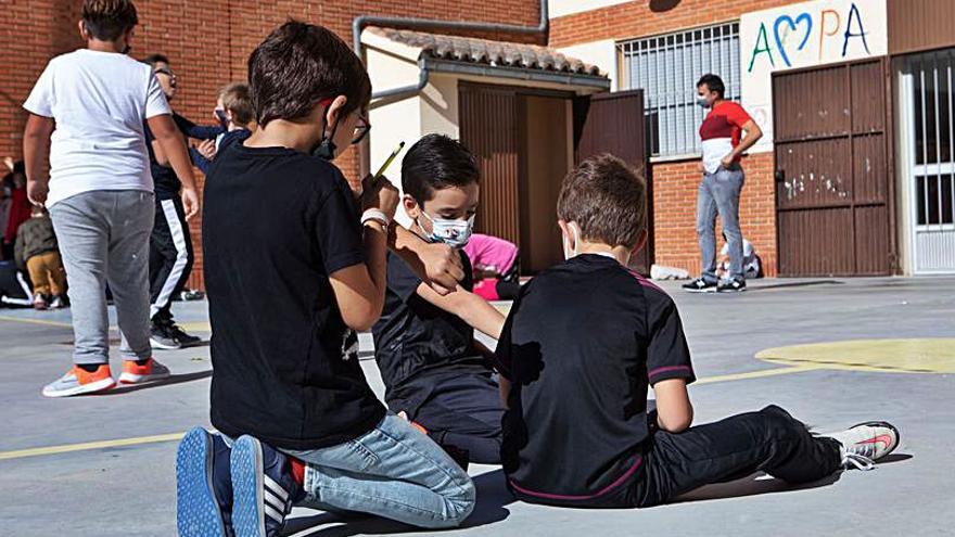 Sobre estas líneas, filas de alumnos en el patio y un grupo de niñas jugando. | Ana Burrieza