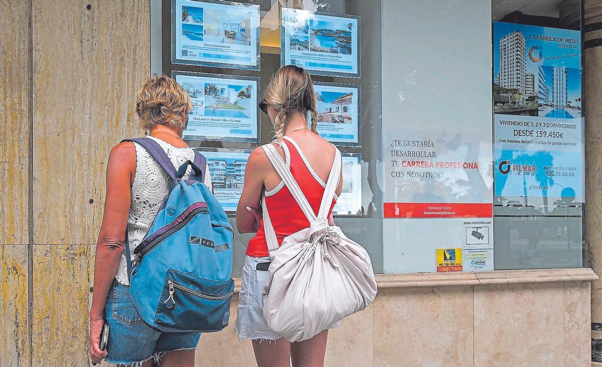 Dos mujeres repasan las ofertas de inmuebles en el escaparate de una agencia inmobiliaria.
