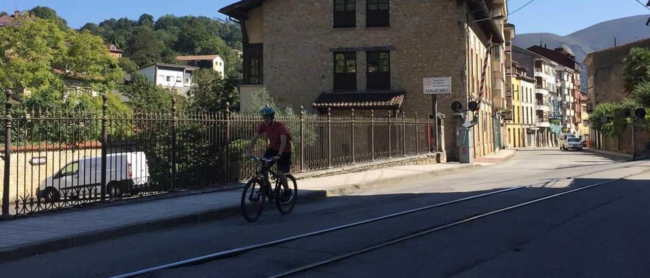 Un ciclista a punto de cruzar el paso a nivel de la avenida de La Cueva, en Infiesto, ayer.