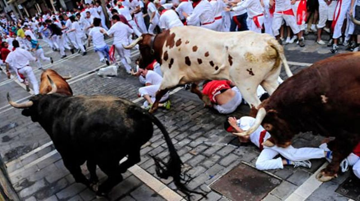 Participants de la festa fugen dels toros pels carrers de Pamplona.