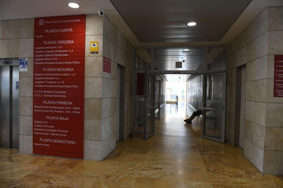 Un hombre sentado en un banco en el acceso al Juzgado de Guardia, en la planta baja de la Ciudad de la Justicia de Murcia.