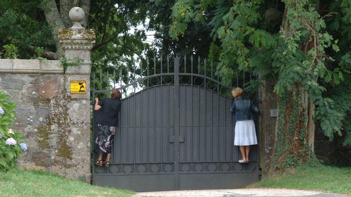 Dos mujeres encaramadas al portalón de entrada del pazo de Meirás para ver los jardines. / CARLOS PARDELLAS