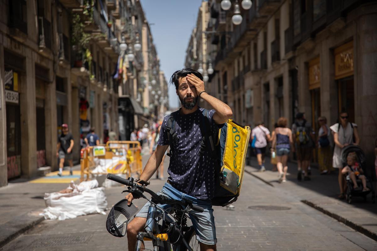 Un trabajador reparte para Glovo durante una ola de calor, en Barcelona.