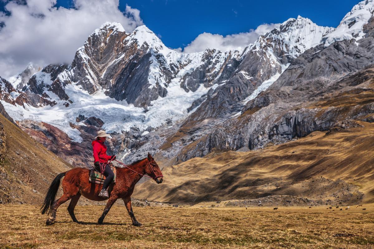 Joven turista montando un caballo en los Andes peruanos, Sudamérica.