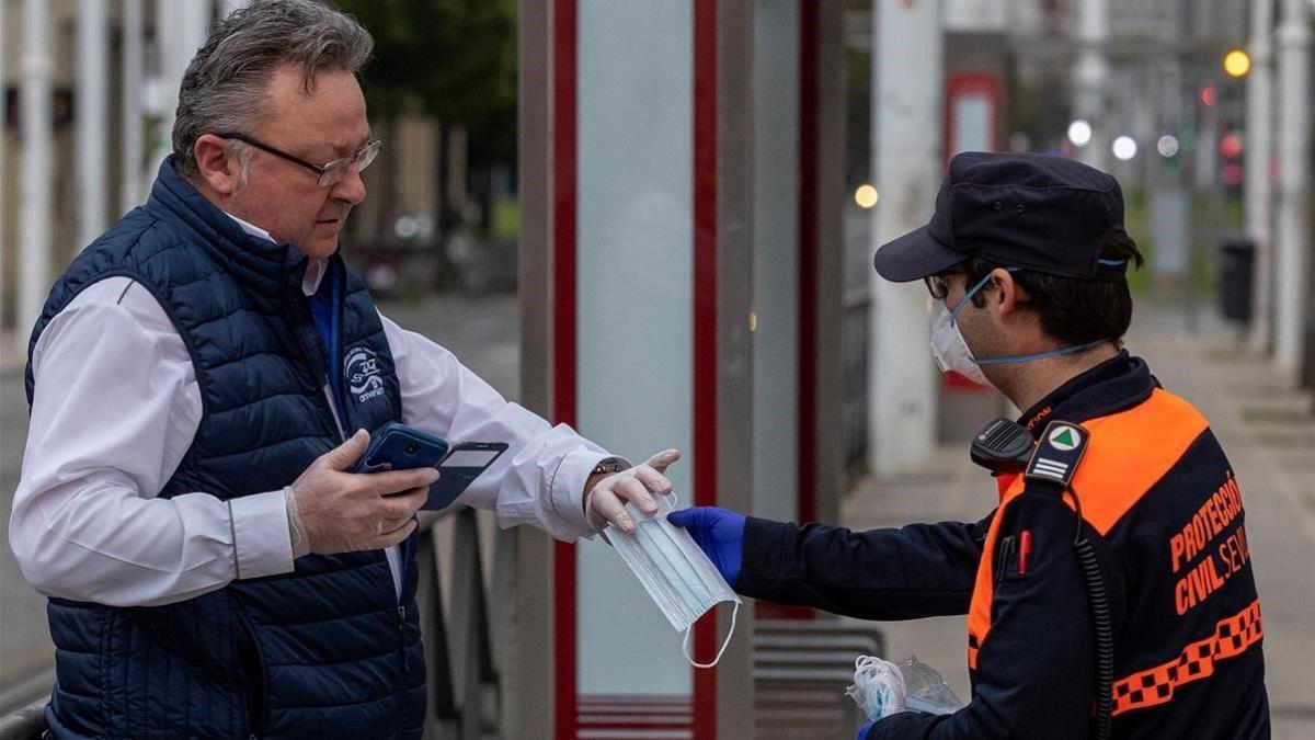 Un voluntario de Proteccion Civil repartiendo mascarillas a los viajeros