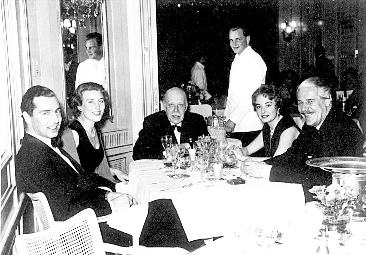 En sus tiempos como camarero, en el Palace de St. Moritz mientras atiende a clientes, entre ellos su tío y padrino, el príncipe Max Egon Fürstenberg -en el centro-..