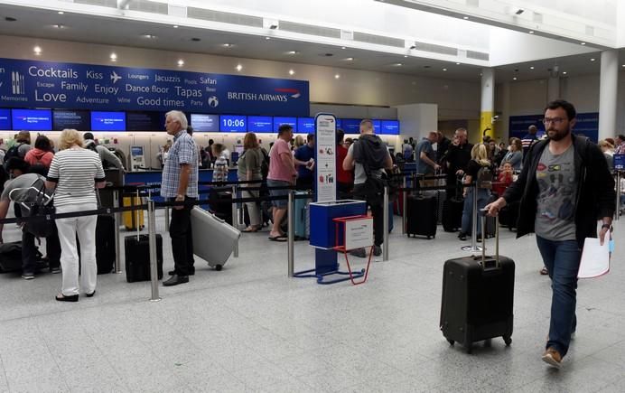 People queue with their luggage for the British ...