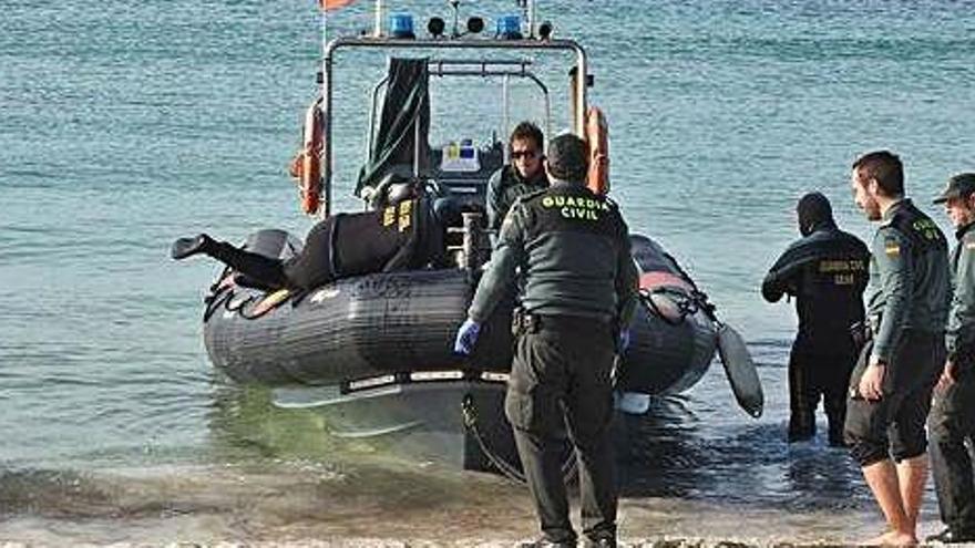 Momento en el que los guardias trasladan desde tierra el cadáver a la lancha de los GEAS de la Guardia Civil.