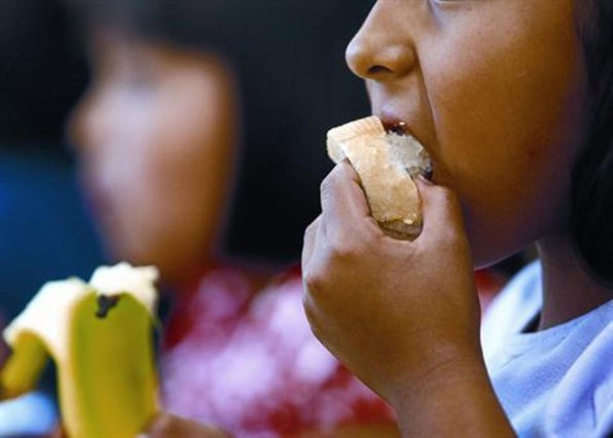 Una nena menja un tros de pa al menjadordel col·legi Sant Josep Oriol de Barcelona.