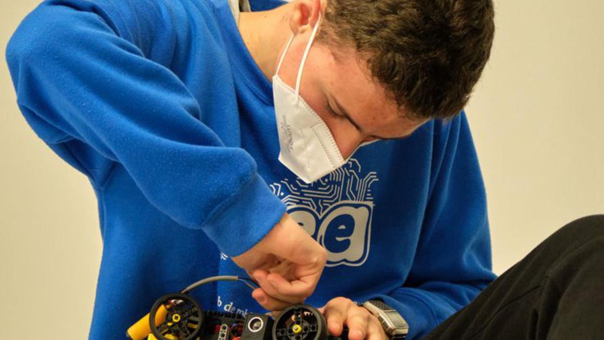 Marc Costa ajusta els últims detalls del seu robot abans de deixar-lo al terra perquè realitzi el mateix exercici que va fer a la World Robot Olympiad.