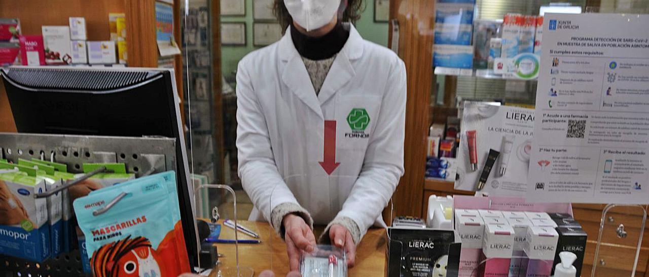 Una farmaceútica en Cangas entrega uno de los kits de saliva para hacer la PCR. |   // GONZALO NÚÑEZ