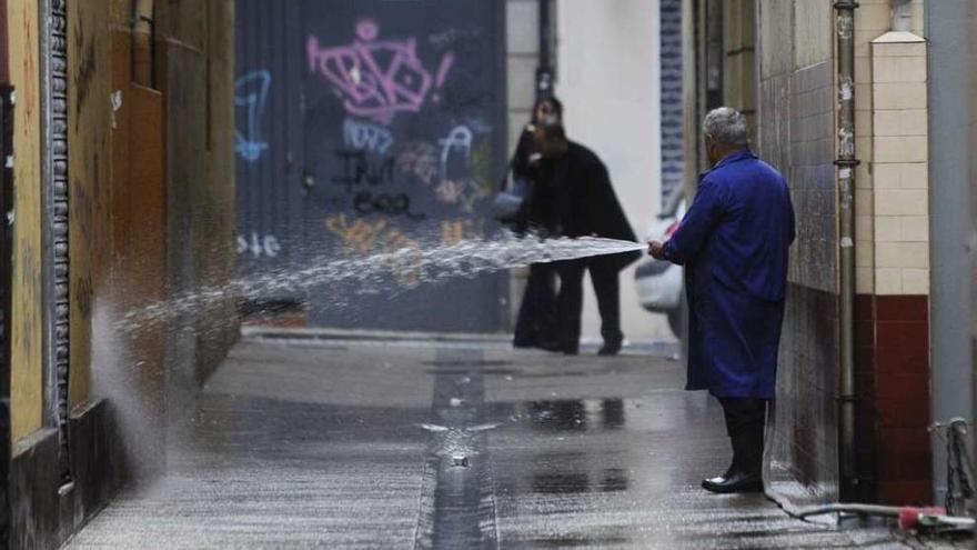 Un hombre riega una calle en la zona del Orzán tras la noche de fin de año de 2012.