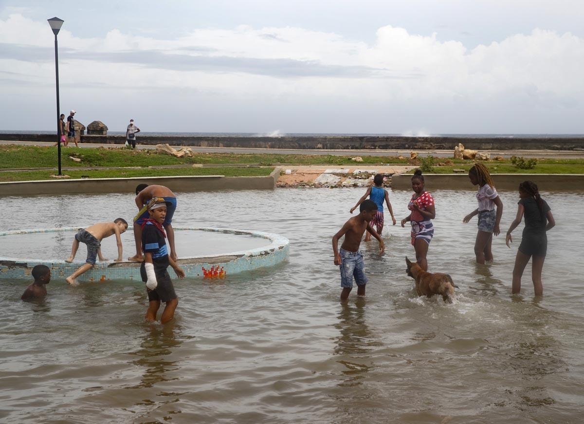 Varios jóvenes se diviertan en el agua, tras el paso del huracán Ian, en La Habana, Cuba.