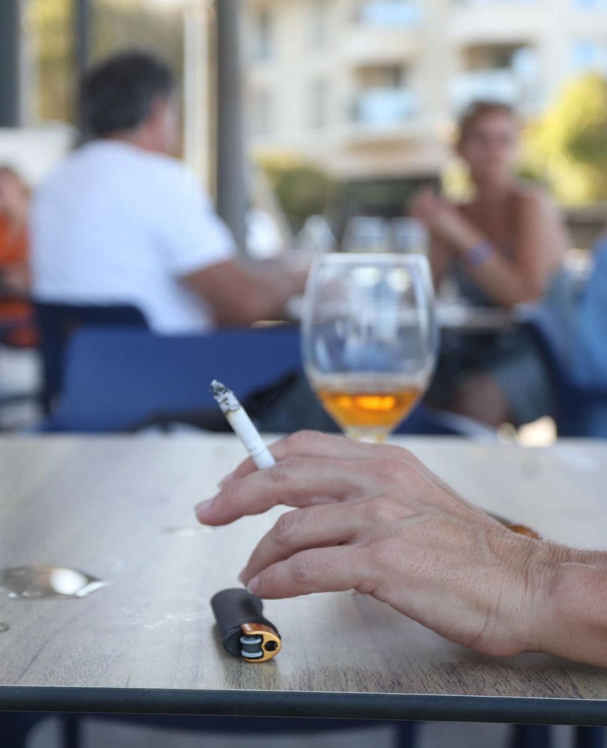 Un client d’una terrassa fuma un cigarret mentre pren una cervesa. | FRANCISCO CALABUIG