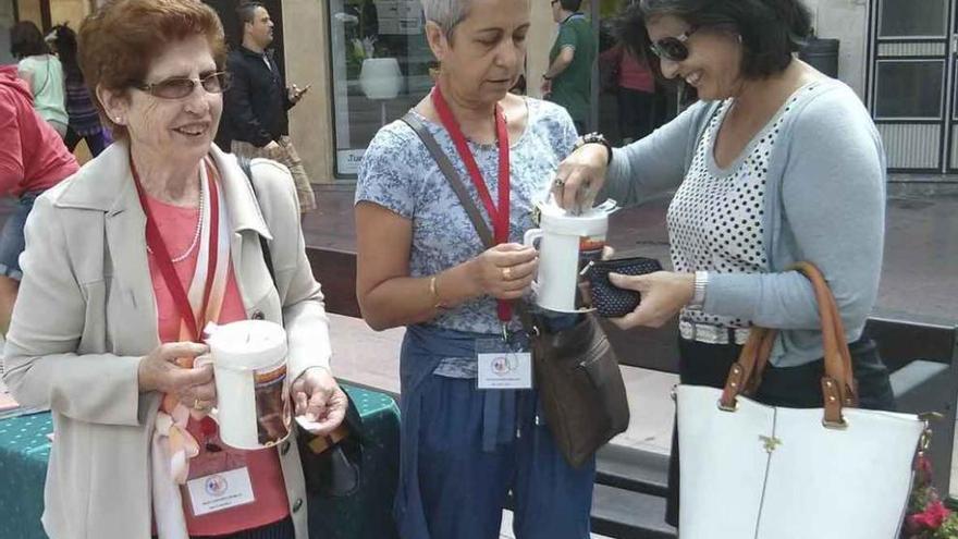 Una mujer colabora con la asociación. En el centro, la presidenta junto a una voluntaria (izquierda).