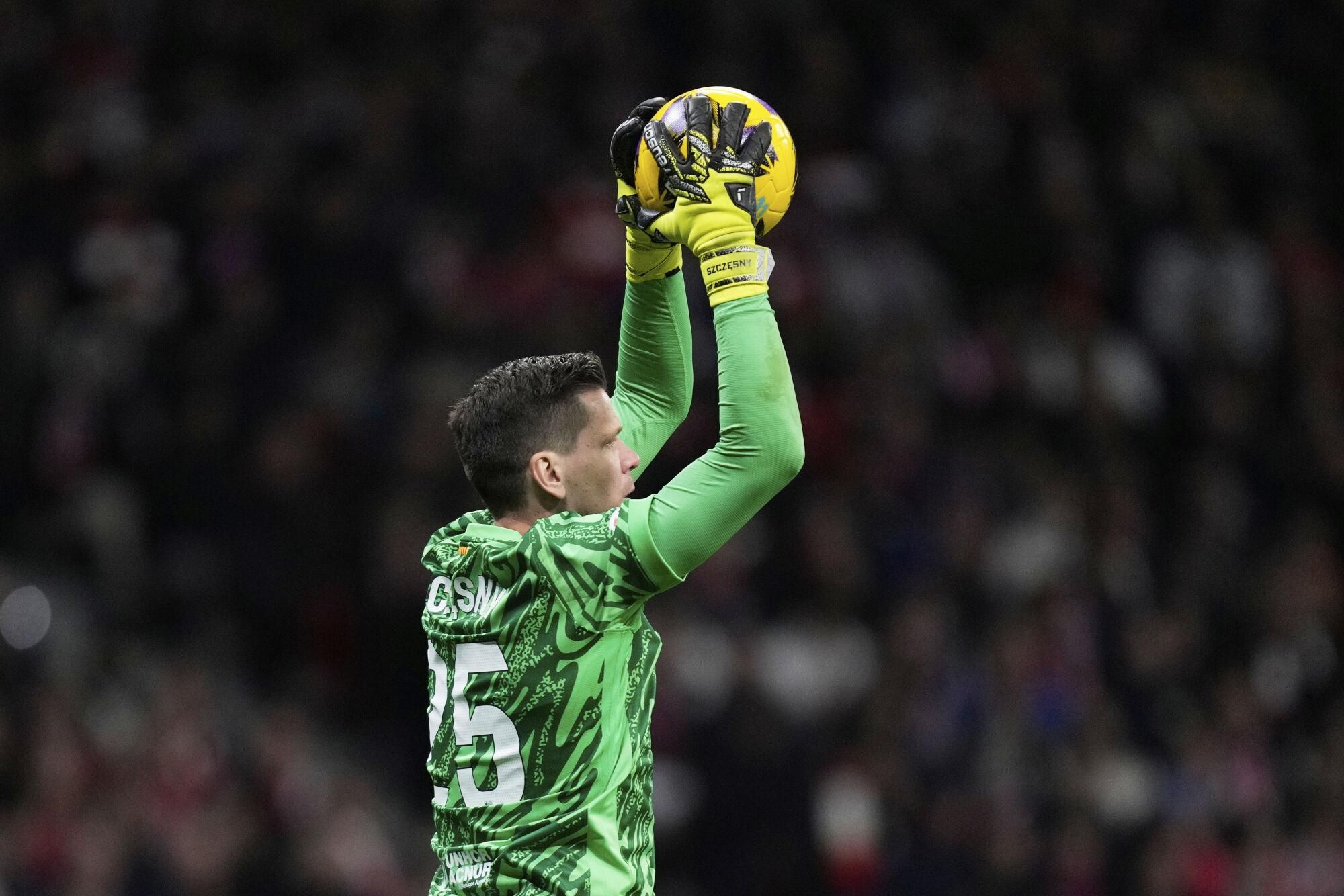 Barcelona's goalkeeper Wojciech Szczesny catches the ball during a La Liga soccer match between Atletico Madrid and FC Barcelona at the Metropolitano stadium in Madrid, Sunday, March 16, 2025. (AP Photo/Bernat Armangue)