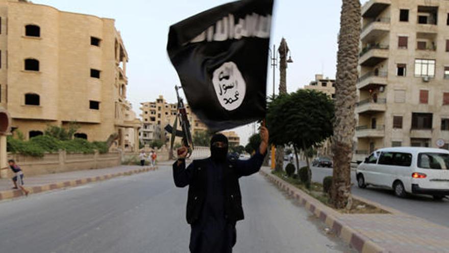 Un miembro del EI, con la bandera negra del grupo terrorista.