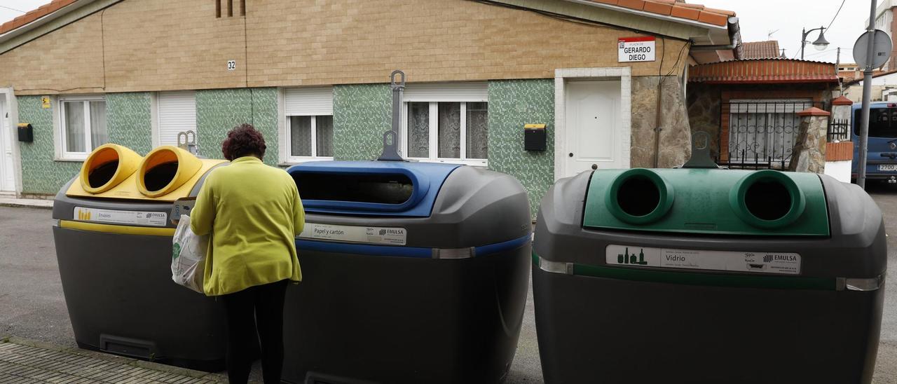 Una mujer tira la basura a un contenedor