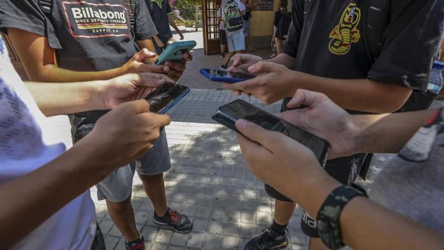 Alumnos con sus teléfonos móviles a las puertas de un instituto de Elche. | ANTONIO AMORÓS