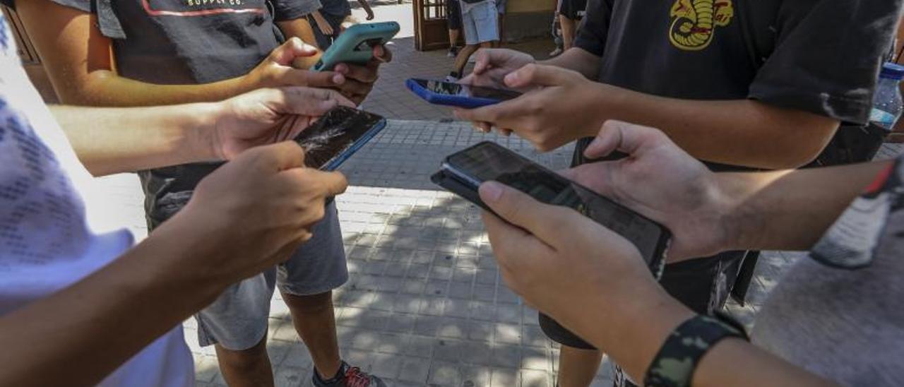 Alumnos con sus teléfonos móviles a las puertas de un instituto de Elche. | ANTONIO AMORÓS