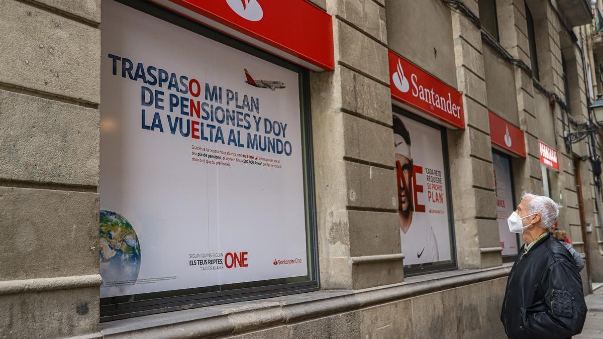 Un hombre observa un anuncio sobre planes de pensiones en una oficina del Santander