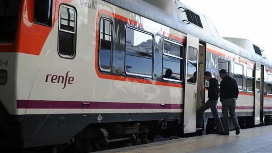 Dos pasajeros se suben a un tren entre A Coruña y Ferrol en la estación de San Cristóbal.  // Juan Varela