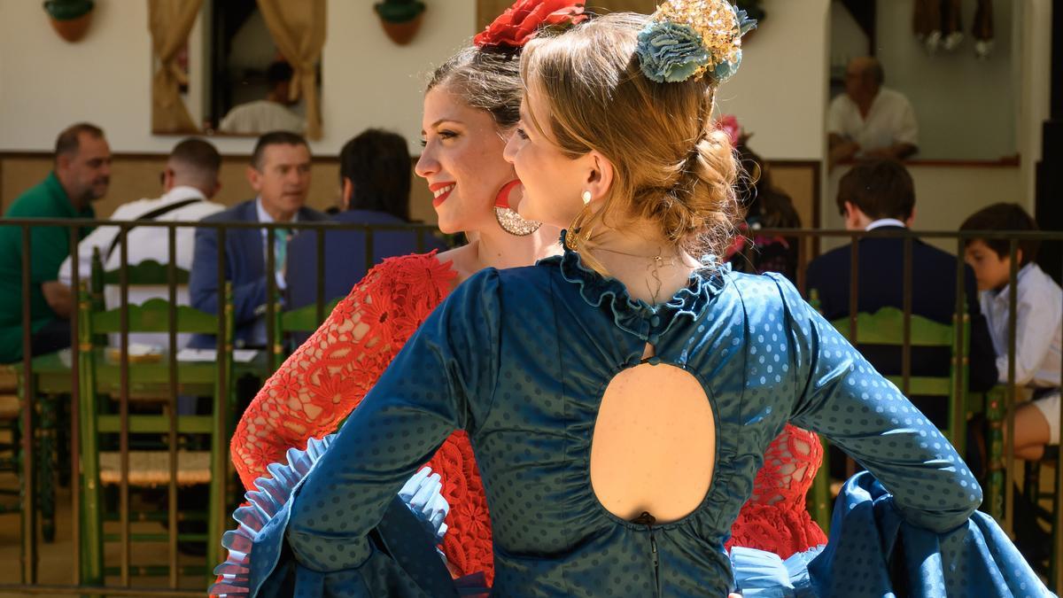 SEVILLA, 14/04/2024.-Dos mujeres vestidas de flamenca este domingo en el Real de la Feria de Abril de Sevilla .-EFE/ Raúl Caro
