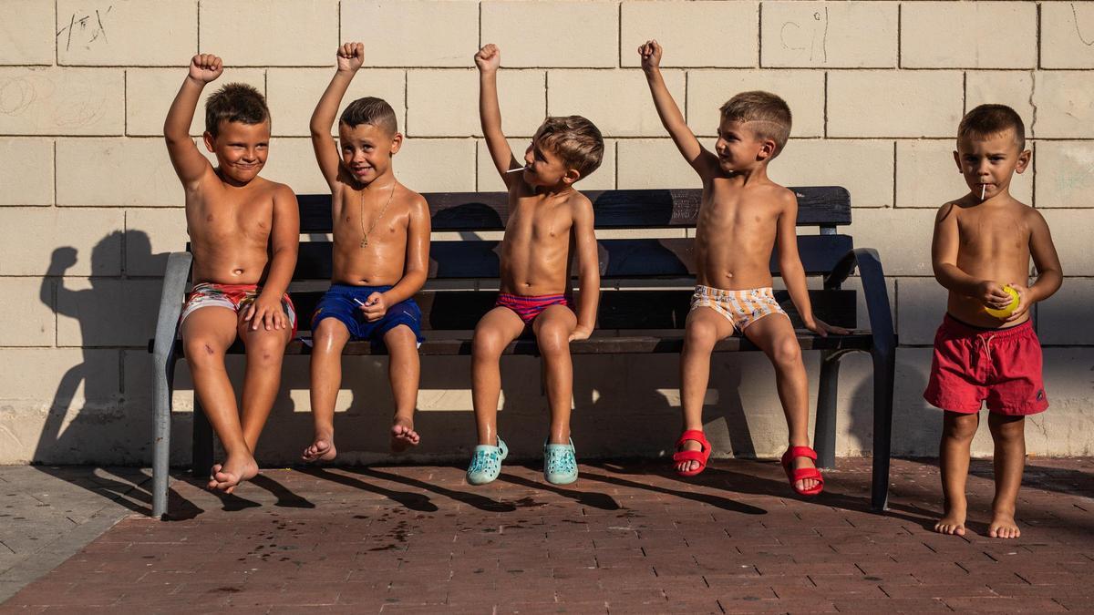 Unos niños juegan al aire libre mientras se refescan con agua, el verano pasado en Santa Coloma de Gramenet.