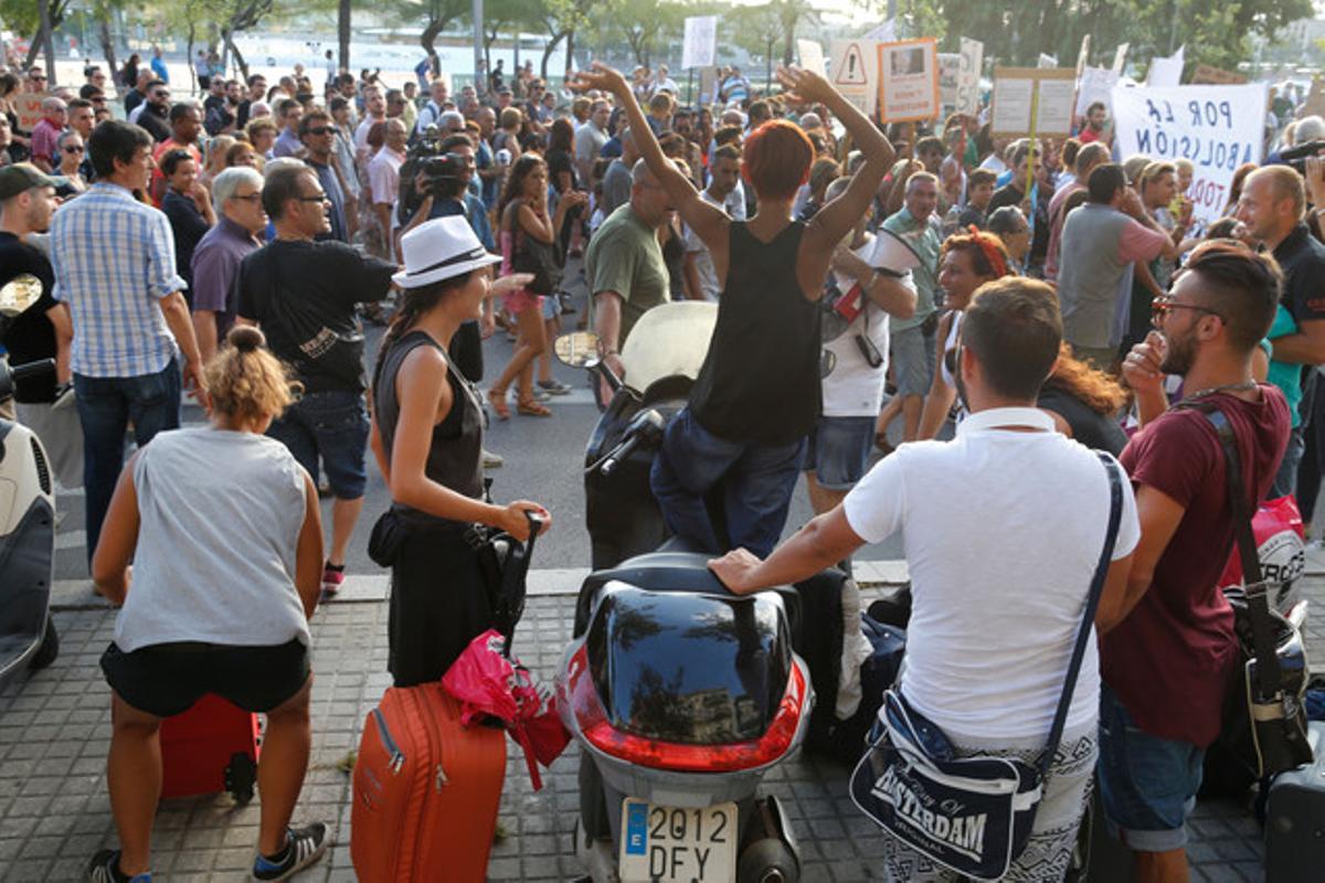 Los vecinos de la Barceloneta pasan manifestándose por Joan de Borbó mientras unos turistas les observan, este sábado.