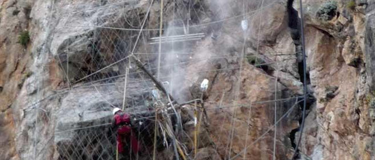 Dos operarios sujetan un bloque en la carretera de la Serra.