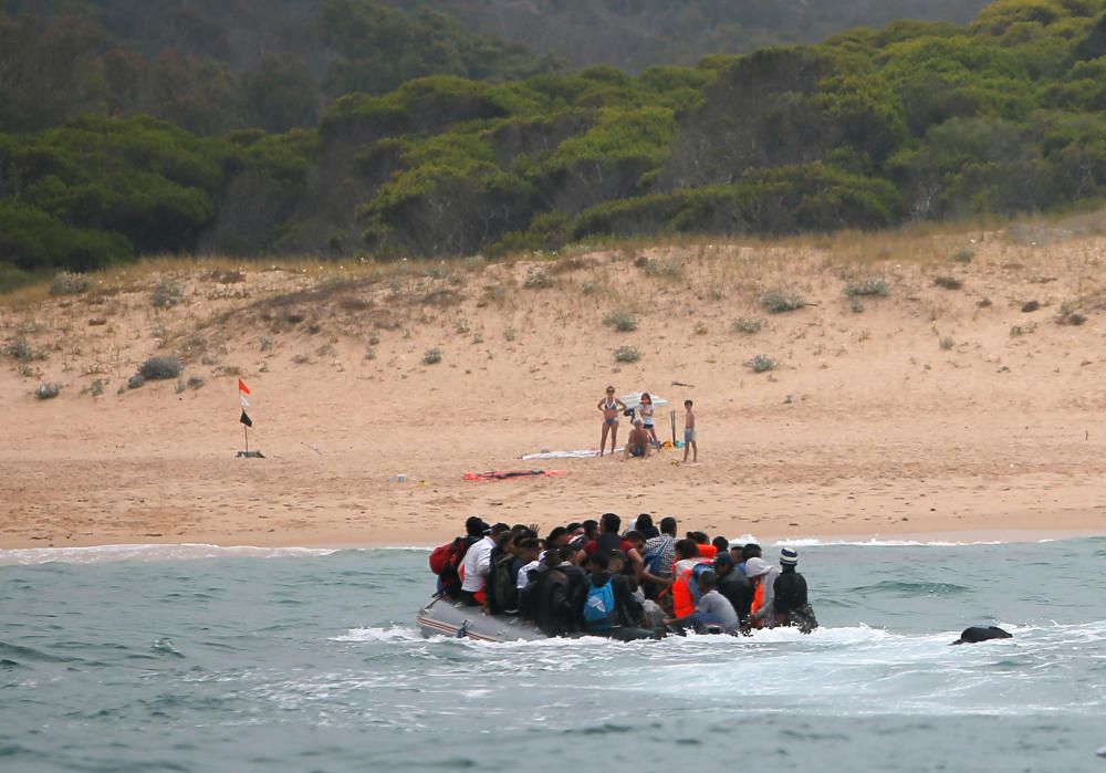 Una patera llega a una playa de Cádiz ante la mirada de los bañistas