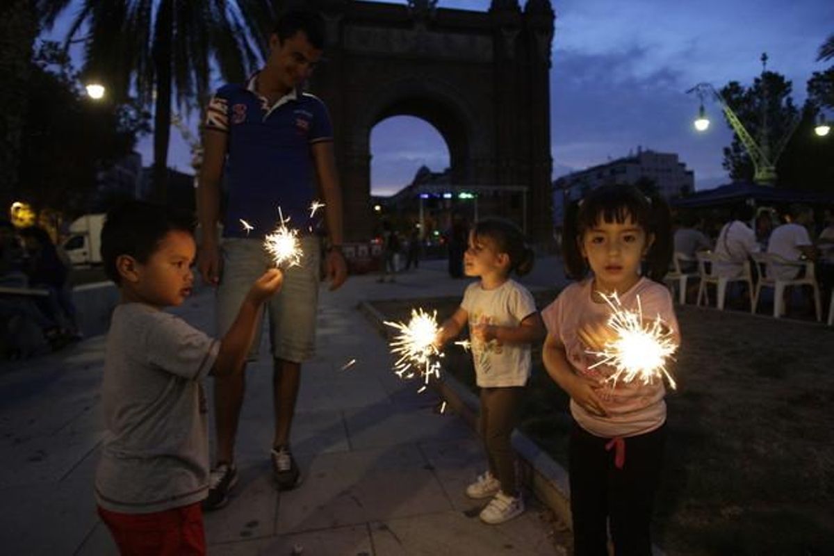 Uns nens juguen amb unes bengales a l’Arc de Triomf de Barcelona.