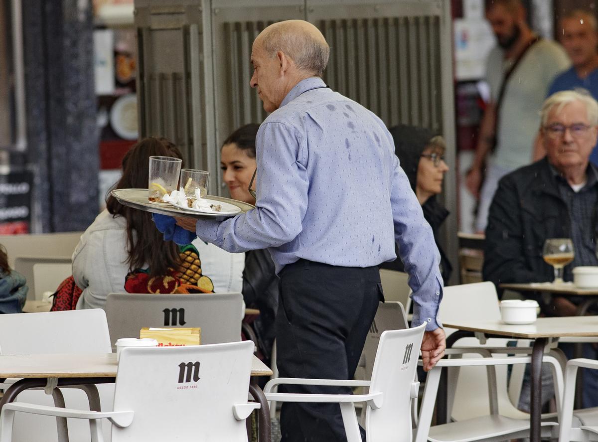 Archivo - Un camarero porta una bandeja en una terraza de un bar de Madrid.