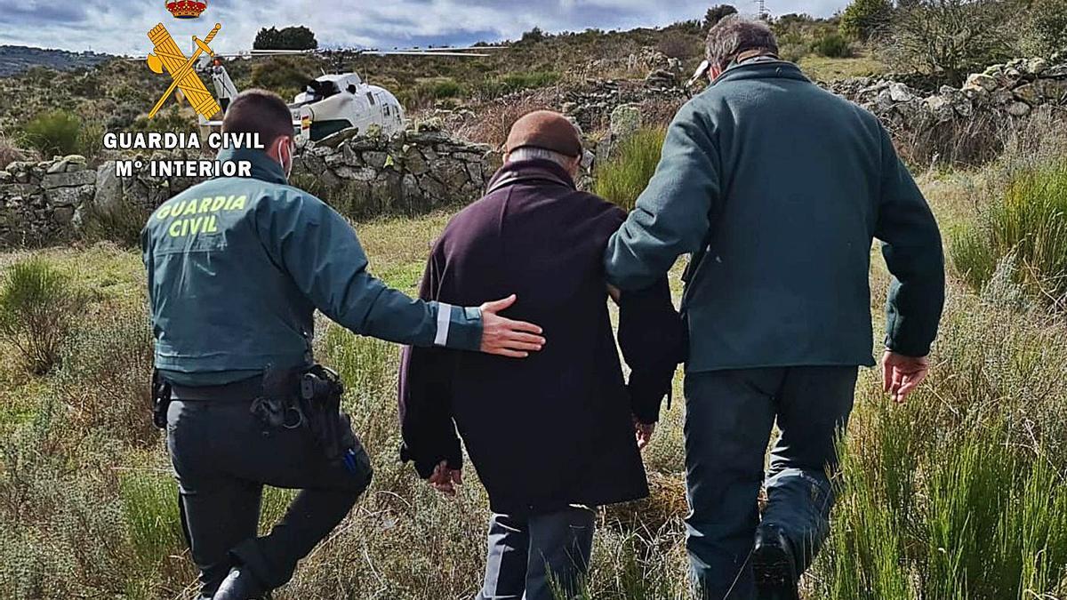 Dos guardias civiles acompañan al hombre rescatado en un paraje de Villalcampo para subirlo al helicóptero. | G. C.