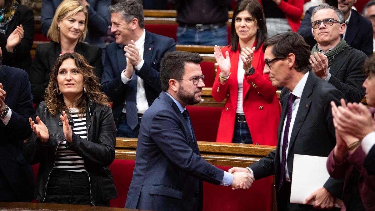 El president Pere Aragonès y el líder del PSC, Salvador Illa, estrechándose la mano en el Parlament