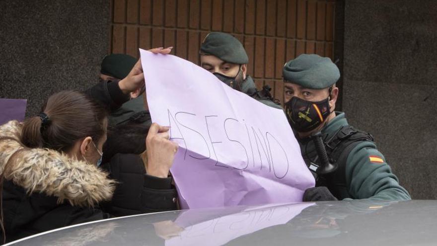 Agentes de la Guardia Civil contienen a jóvenes con carteles de asesino a la puerta del juzgado de Sueca. | PERALES IBORRA