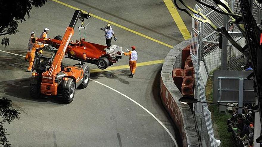 Una grúa se lleva el Ferrari de Felipe Massa tras romper el motor en la primera clasificatoria en Singapur. / the straits times