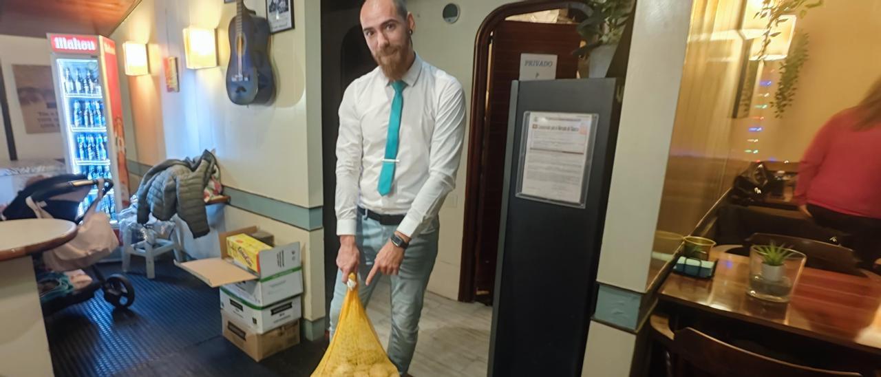 Sergio Rodríguez, con el saco de patatas con el que robaron de la caja en su cafetería de Mieres. | A. Velasco