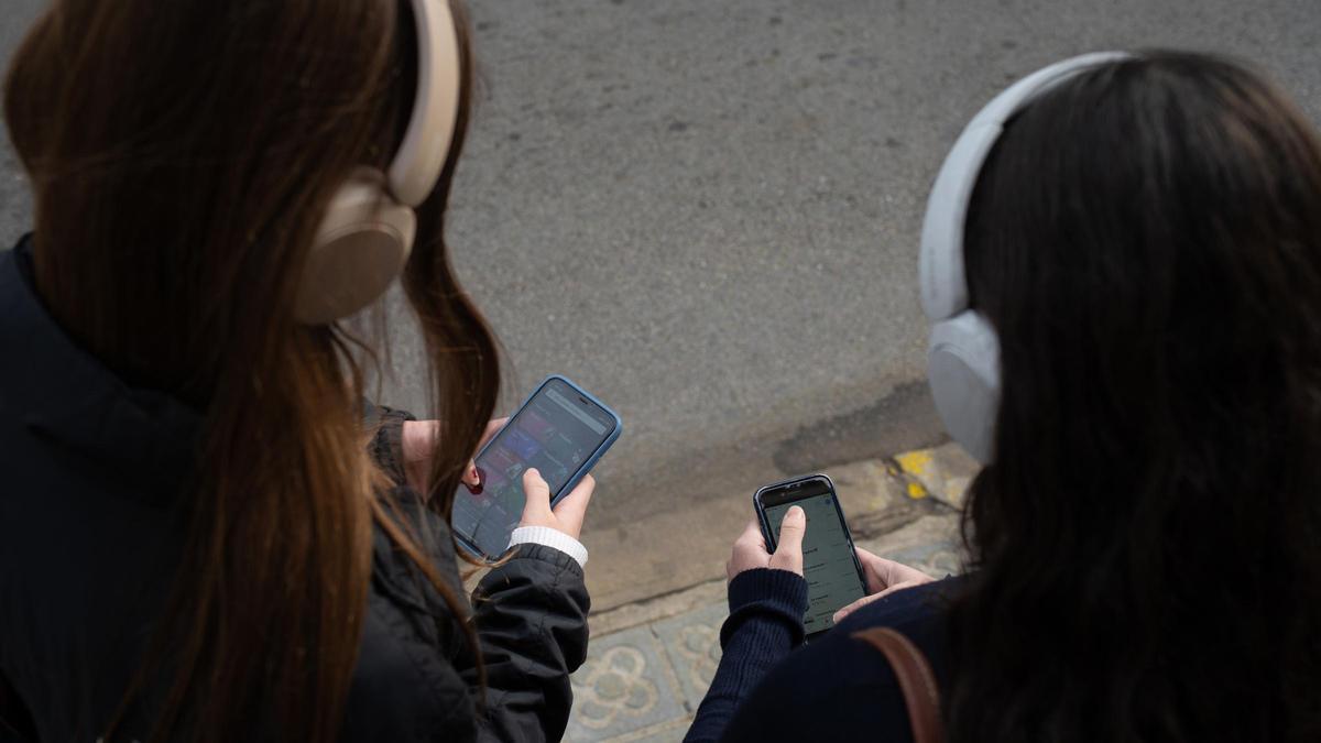 Dos personas utilizan el teléfono móvil.
